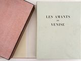 an open book sitting on top of a white table next to a pink book