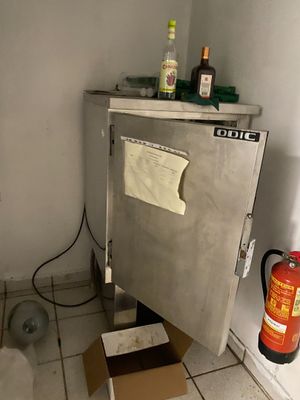 a small refrigerator in the corner of a room with a fire extinguisor