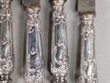 four silverware knives and a knife holder on a white surface