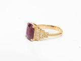 a close up of a gold ring with a purple stone and diamonds