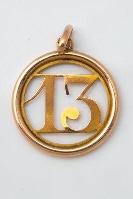 a close up of a gold pendant with the number thirteen on it