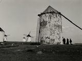 photo en noir et blanc d'un groupe de personnes debout devant un moulin à vent