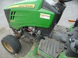 a green lawn mower sitting on the side of the road