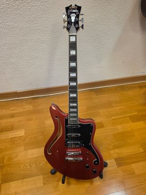 a red electric guitar sitting on top of a hard wood floor