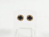 une paire de boucles d'oreilles noires et dorées présentées sur un présentoir transparent