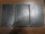 trois livres noirs posés les uns à côté des autres sur une table en bois