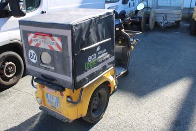 un chariot élévateur sur lequel est posée une caisse, dans un parking