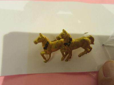 someone is holding a pair of gold horses on a pink and white surface