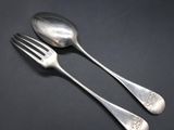 two silver spoons and a fork on a black surface