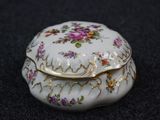a small white box with flowers on it on a black surface