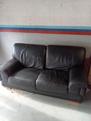 a black leather couch sitting in a room next to a wall