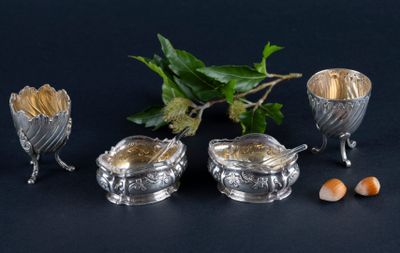 three silver dishes with spoons and spoons next to a plant