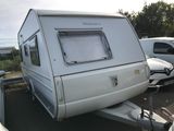une petite caravane blanche garée sur un parking