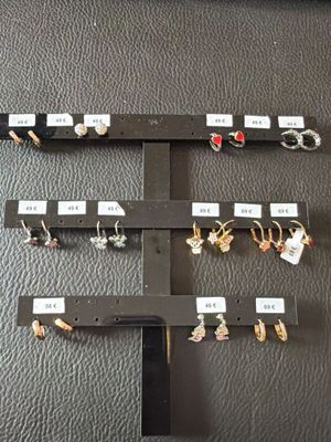 several pairs of earrings are displayed on a display rack on a table