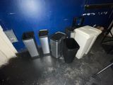 several trash cans are lined up against a blue wall in a room