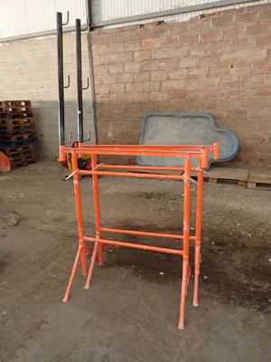orange scaffolding stands in a warehouse with pallets of wood in the background