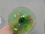 a person holding a green wine glass in their hand