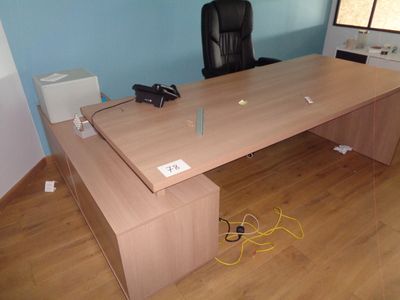 un grand bureau en bois avec une chaise noire dans un coin