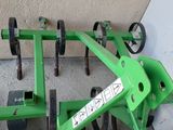 a green plow sitting on the ground next to other tools