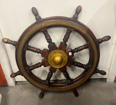 une roue de bateau avec un centre doré accrochée au mur