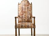 an old chair with a patterned upholstered back and arms
