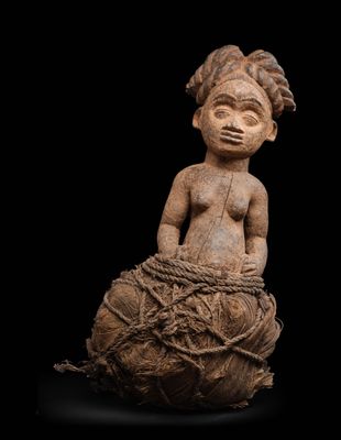 une statue représentant une femme assise sur un morceau de bois