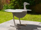a white duck sitting on a table in the yard