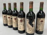 six bottles of wine are lined up in a row on a white surface