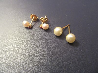 two pairs of pearl earrings on a black surface
