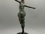 Une statue représentant une femme en robe verte se dresse sur un socle noir.