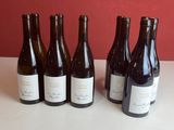 six bouteilles de vin sont alignées sur une table