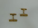 two pairs of gold cufflinks on a white surface