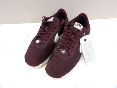 une paire de baskets bordeaux avec des lacets blancs sur un fond blanc