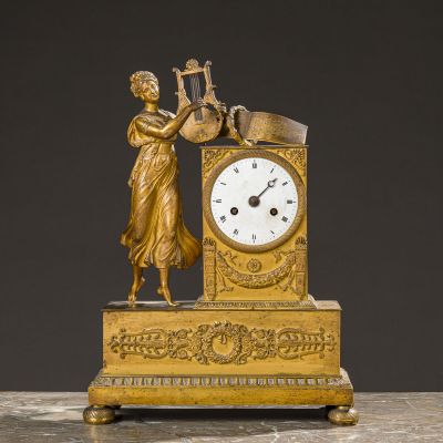 a gold clock with a woman playing the harp