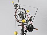 a sculpture of a spinning machine with yellow balls on it