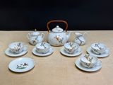 une table sur laquelle sont posés une théière, des tasses et des soucoupes