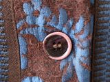 a close up of a button on a blue and brown shirt