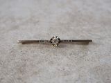 a close up of a silver tie bar with a flower on it