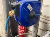 un réservoir bleu muni d'un tuyau, placé contre un mur