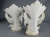 two white vases with leaves on them on a table