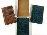 Quatre livres sont alignés sur une surface blanche ; l'un est vert et l'autre est marron.
