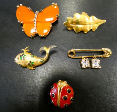 four pieces of brooches and a pin on a black surface