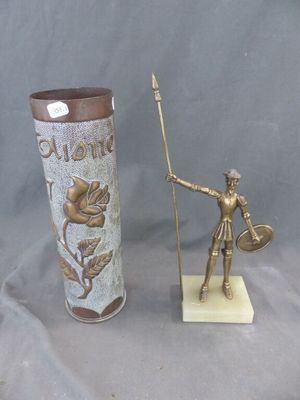 une statue représentant un homme tenant une lance à côté d'un vase