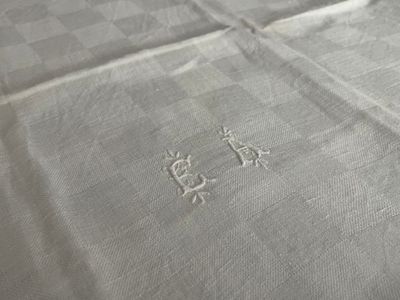 a close up of a bed with a white sheet with a monogram on it