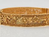 a close up of a gold bracelet on a white surface