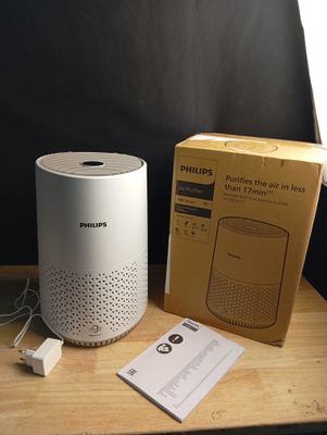 un haut-parleur blanc posé à côté d'une boîte sur une table