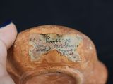 a hand holding a small vase with writing on it