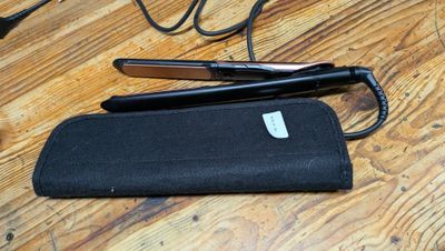 une paire de ciseaux et un étui noir posés sur une table en bois