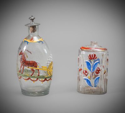 two glass bottles with designs on them sitting next to each other