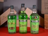 three bottles of green liquor sitting next to each other on a table